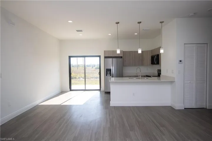 Kitchen featuring sink, light brown cabinets, appliances with stainless steel finishes, and hanging light fixtures