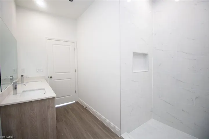 Maser Bathroom featuring vinyl-type flooring, tiled shower, and vanity