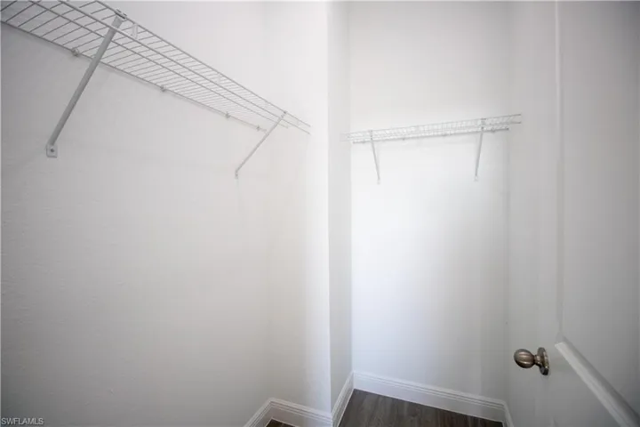 Walk in closet with dark vinyl-type flooring