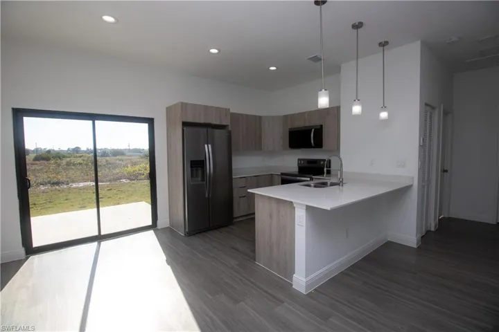 Kitchen with appliances with stainless steel finishes, sink, hanging light fixtures, kitchen peninsula, and a breakfast bar area