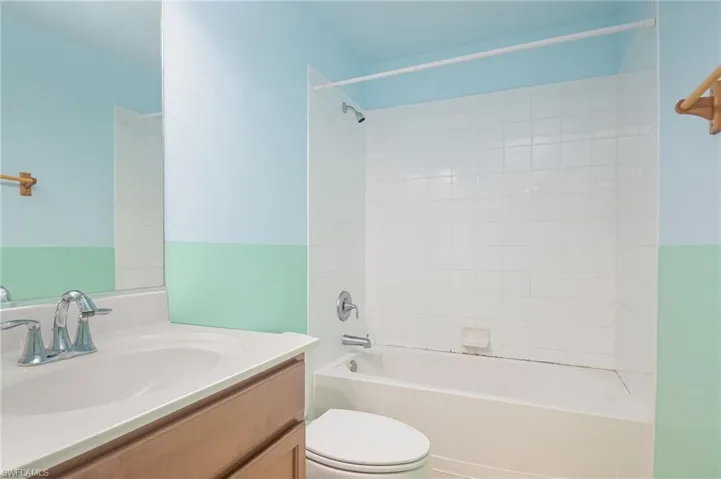 Full bathroom featuring tiled shower / bath, vanity with extensive cabinet space, and toilet