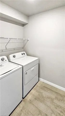 Laundry area with washing machine and dryer and light hardwood / wood-style floors