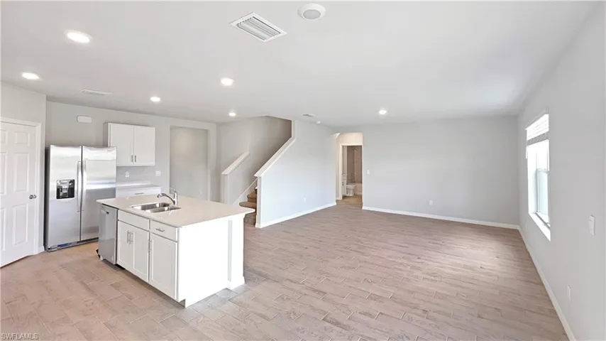 Kitchen featuring sink, light wood-type flooring, an island with sink, white cabinetry, and stainless steel appliances