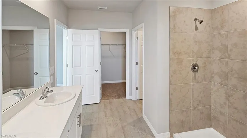 Master Bathroom featuring a tile shower, hardwood / wood-style floors, and vanity