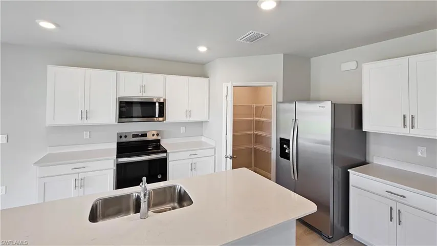 Kitchen featuring sink, white cabinets, and stainless steel appliances