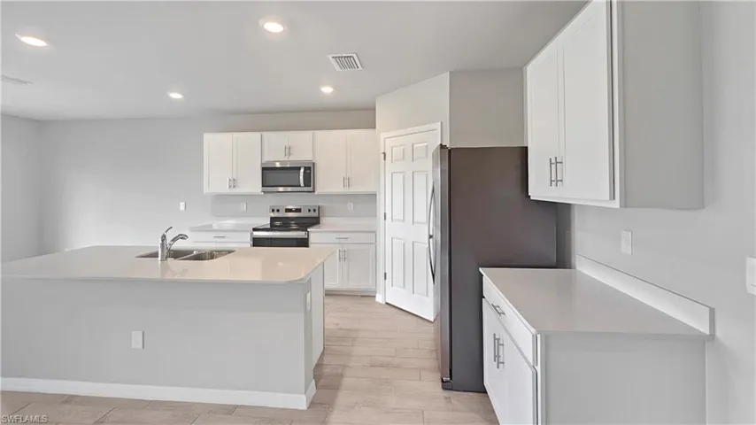 Kitchen featuring white cabinetry, sink, light hardwood / wood-style floors, a center island with sink, and appliances with stainless steel finishes