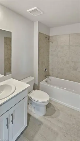 Full bathroom with tiled shower / bath combo, toilet, and vanity