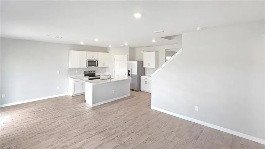 Kitchen featuring sink, stainless steel appliances, light hardwood / wood-style flooring, an island with sink, and white cabinets
