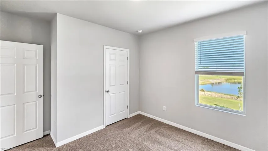 Unfurnished bedroom featuring carpet, a water view, and multiple windows