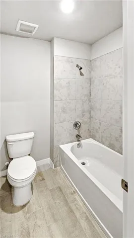 Bathroom featuring tiled shower / bath combo and toilet