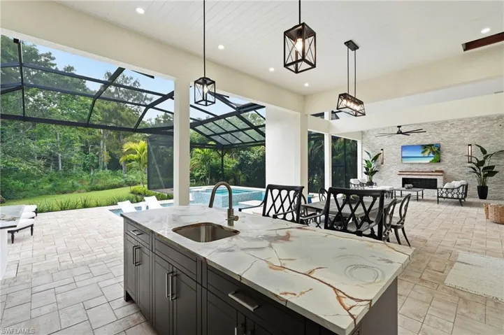 Kitchen island with a built-in sink, stone countertop, and pendant lighting