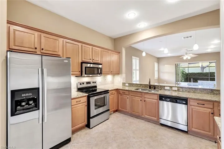 Kitchen featuring light stone counters, stainless steel appliances, sink, and tasteful backsplash