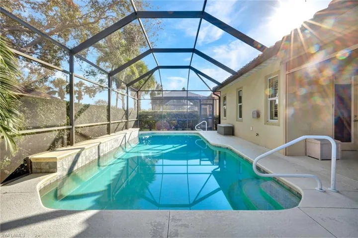 View of pool with a patio area and glass enclosure
