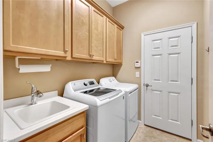 Laundry area featuring cabinets, washing machine and dryer, sink, and light tile patterned floors