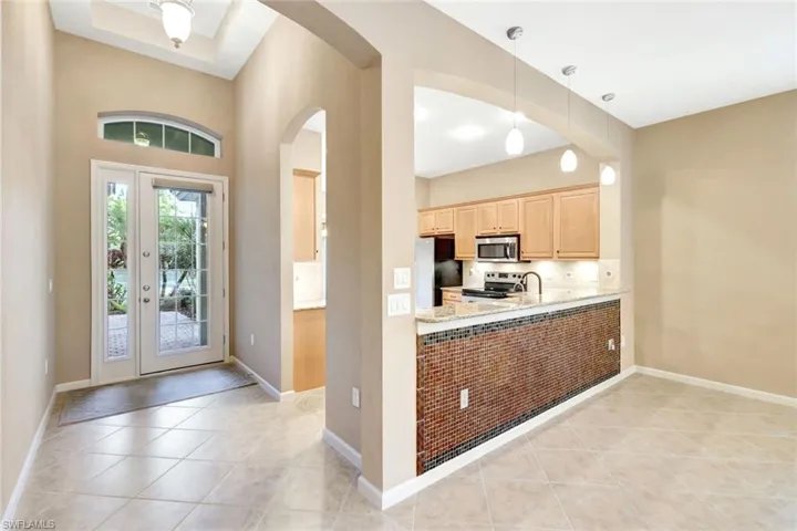 Kitchen featuring stainless steel appliances, light brown cabinets, light tile patterned floors, and decorative light fixtures