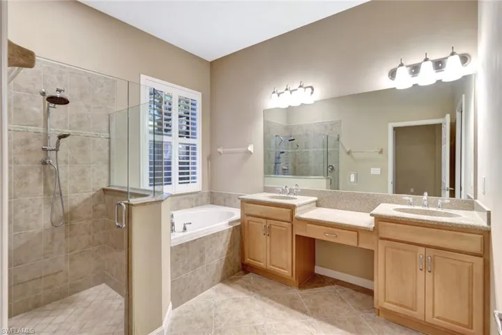 Bathroom featuring tile patterned flooring, shower with separate bathtub, and vanity