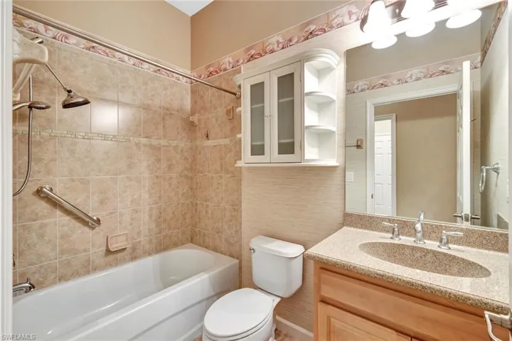 Full bathroom featuring tiled shower / bath combo, vanity, and toilet