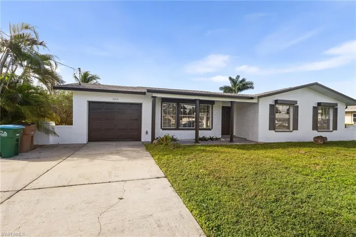 Ranch-style house with concrete driveway, a garage, a front yard, brick siding, and roof with shingles