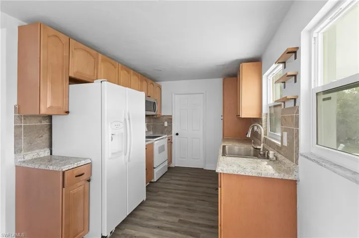 Kitchen with white appliances, tasteful backsplash, dark wood-style floors, and open shelves