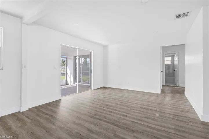 Empty room featuring wood finished floors, recessed lighting, and beamed ceiling