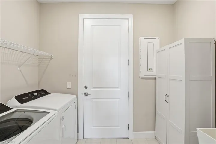 Dedicated laundry room with utility sink and standalone storage unit.