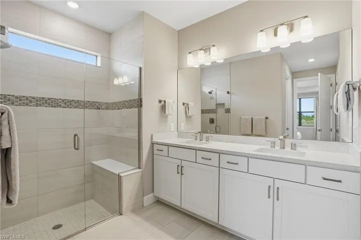 Primary bathroom with double vanity and expansive walk-in shower with bench seating.