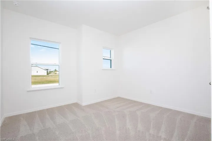 Unfurnished room with baseboards and light colored carpet