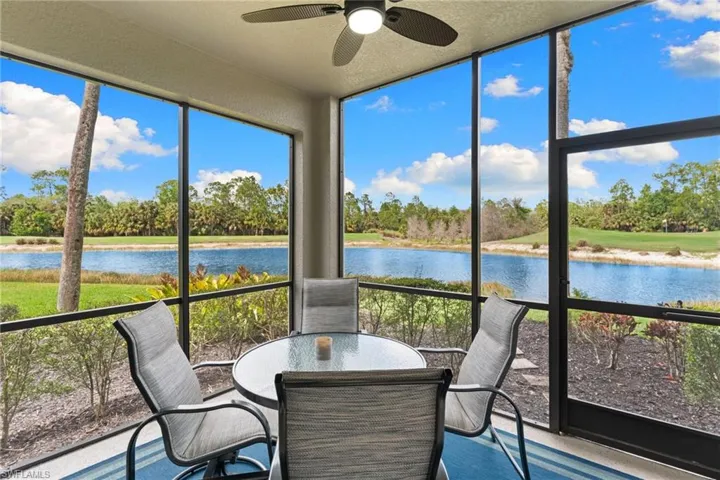 Sunroom / solarium featuring view of wooded area, a water view, and a textured ceiling