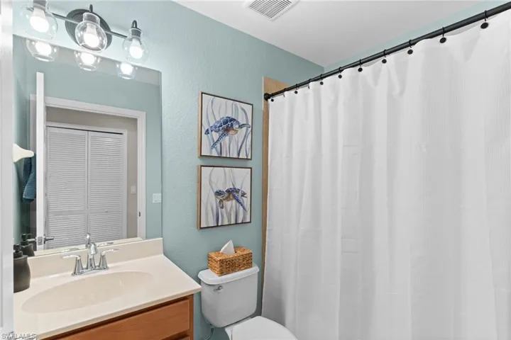Bathroom featuring vanity, curtained shower, a textured wall, and a closet