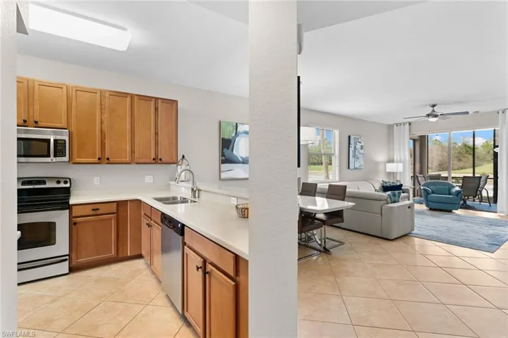 Kitchen featuring light countertops, stainless steel appliances, light tile patterned flooring, wood finish cabinetry, and open floor plan
