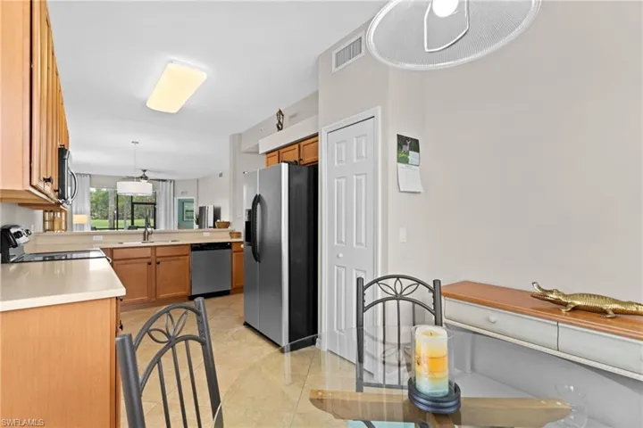 Kitchen with light countertops, stainless steel appliances, wood finish cabinets, hanging light fixtures, and light tile patterned flooring