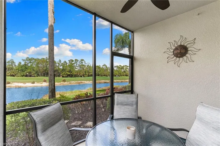 Sunroom featuring outdoor dining area, a water view, view of scattered trees, and a ceiling fan
