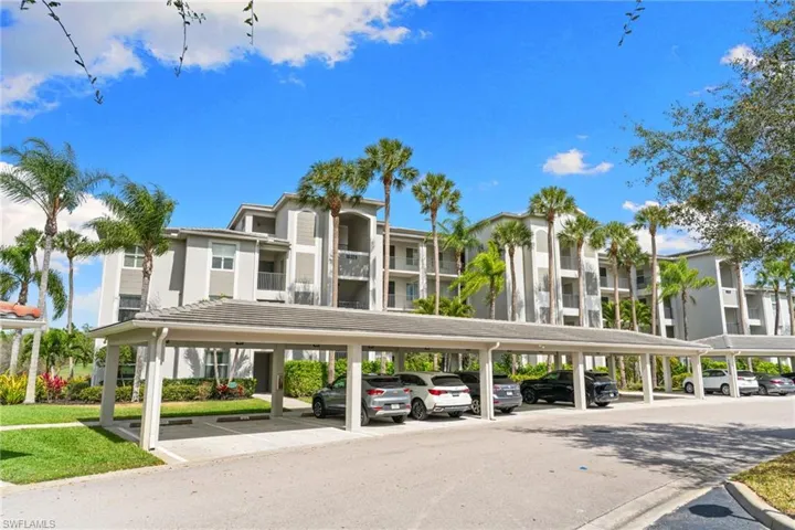 View of apartment building / complex featuring covered parking