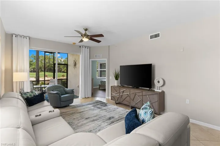 Living room with light tile patterned floors and a ceiling fan