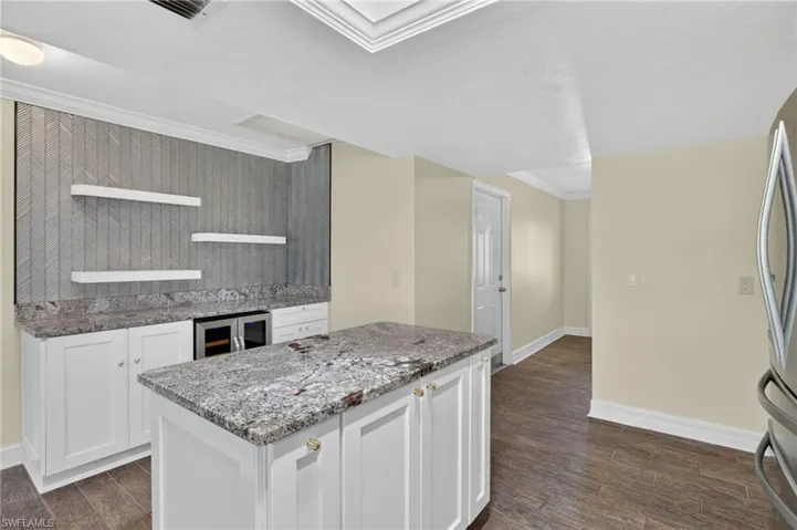 Built-in cabinetry with stone countertops, integrated beverage refrigerator, and open shelving