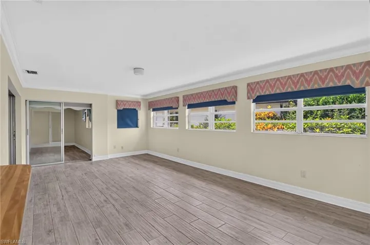 Wood-finish flooring, multiple windows, crown molding, and sliding glass doors