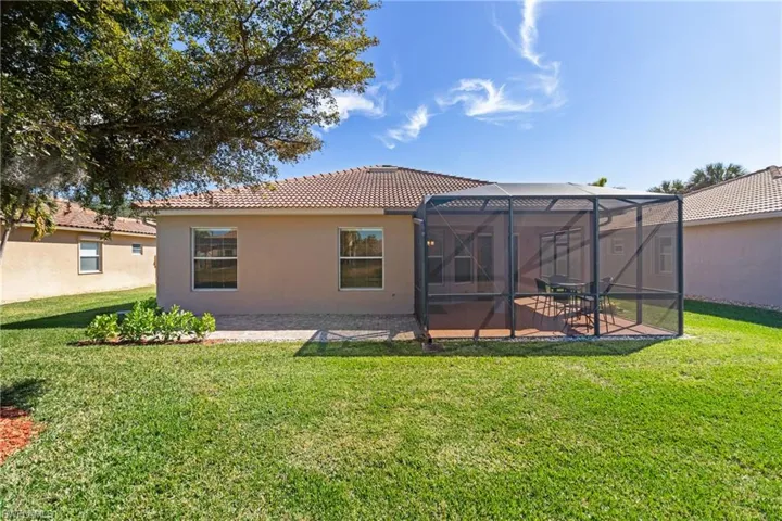 Back of property featuring a lanai, a lawn, and a patio area