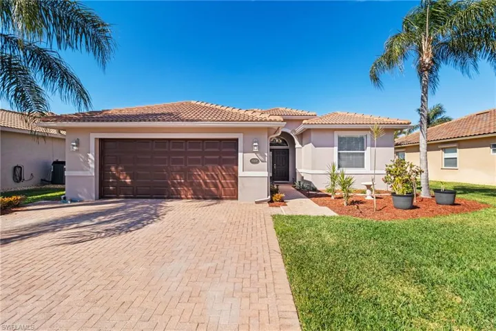 Mediterranean / spanish-style house with central AC unit, a garage, and a front lawn