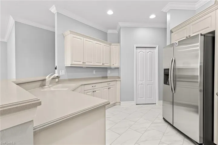 Kitchen with stainless steel fridge with ice dispenser, crown molding, sink, and kitchen peninsula