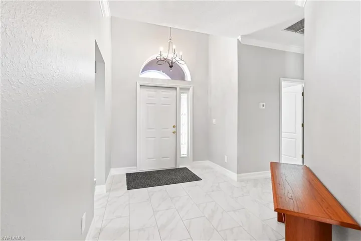 Entrance foyer featuring crown molding and a notable chandelier