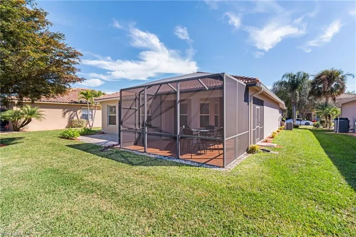 Back of property featuring a lanai, a lawn, and a patio area