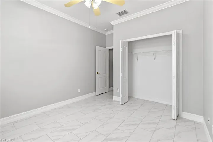 Unfurnished bedroom with crown molding, a closet, and ceiling fan