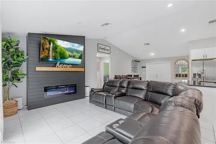 Tiled living room featuring sink, a large fireplace, and lofted ceiling