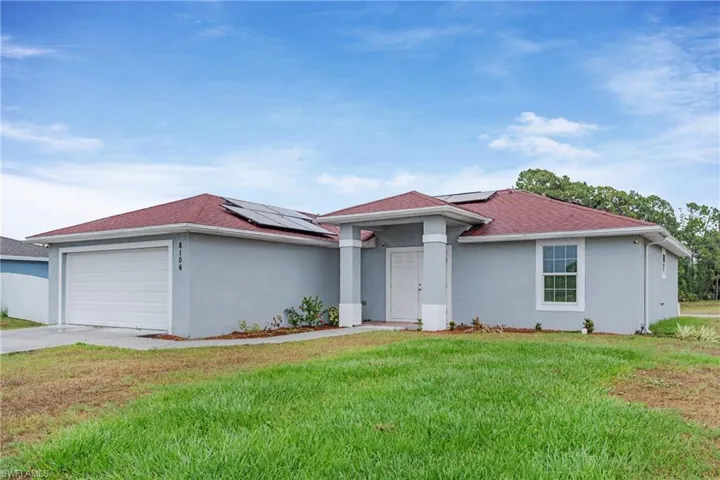 View of front of house featuring a front lawn, a garage, and solar panels