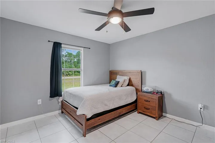 Bedroom with ceiling fan and light tile flooring