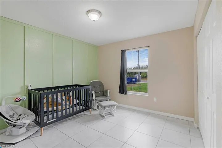 Bedroom with light tile flooring, a closet, and a crib