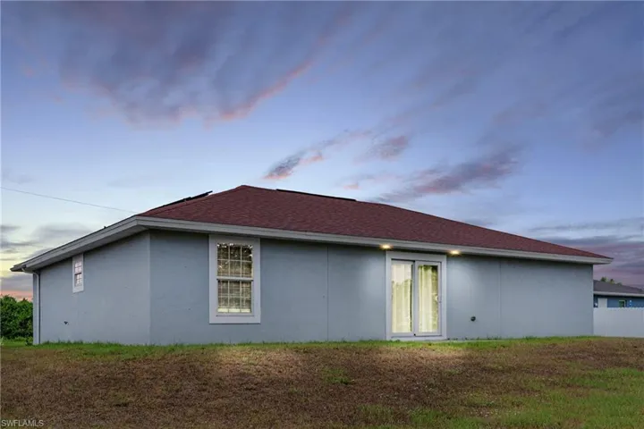 Back house at dusk with a yard