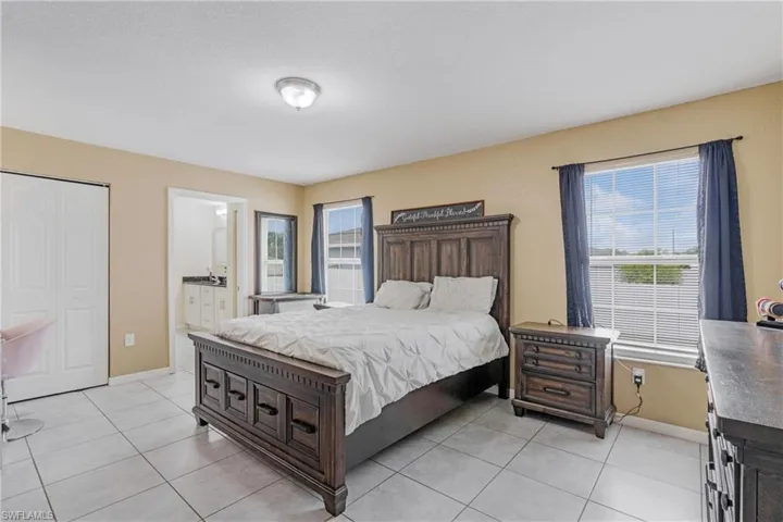 Bedroom with ensuite bathroom and light tile floors
