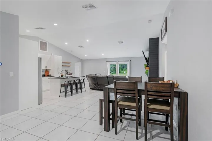 Tiled dining area featuring lofted ceiling