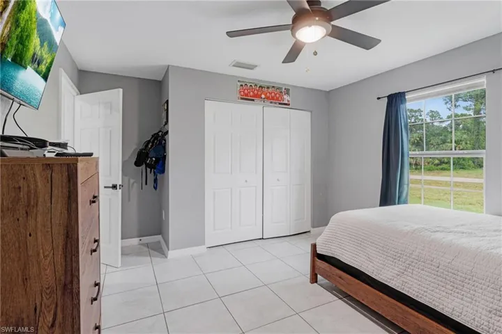 Tiled bedroom featuring ceiling fan and a closet